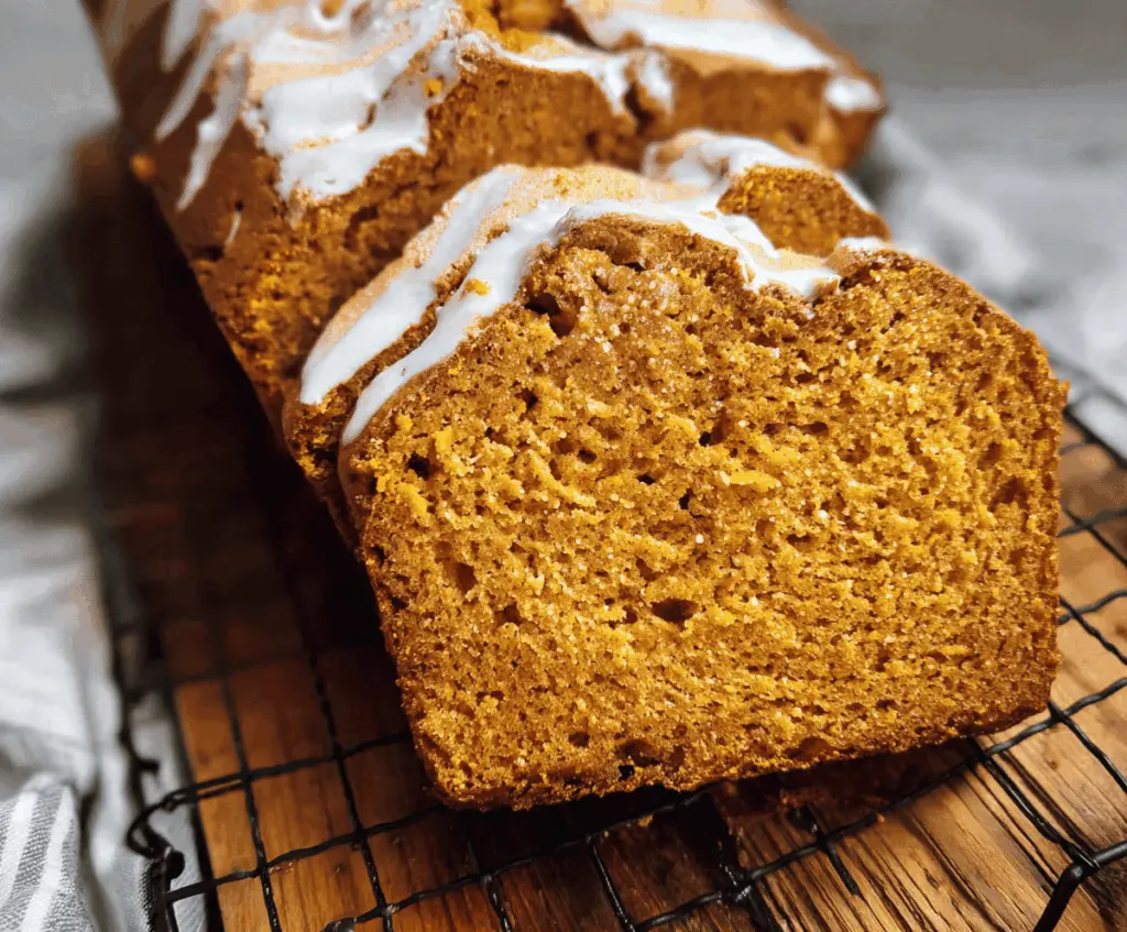 Sweet potato bread loaf with a moist, fluffy texture topped with a sprinkle of cinnamon, served on a rustic wooden surface.