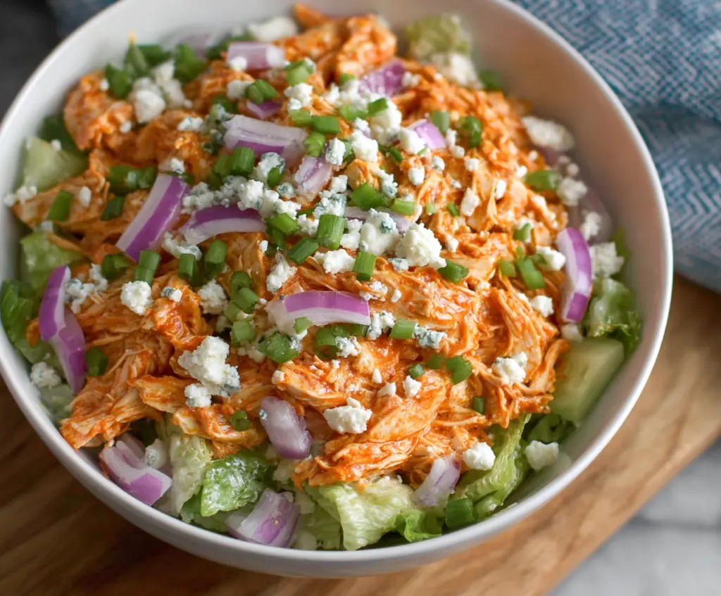 Fresh buffalo chicken salad with crisp vegetables and tangy dressing served in a bowl.