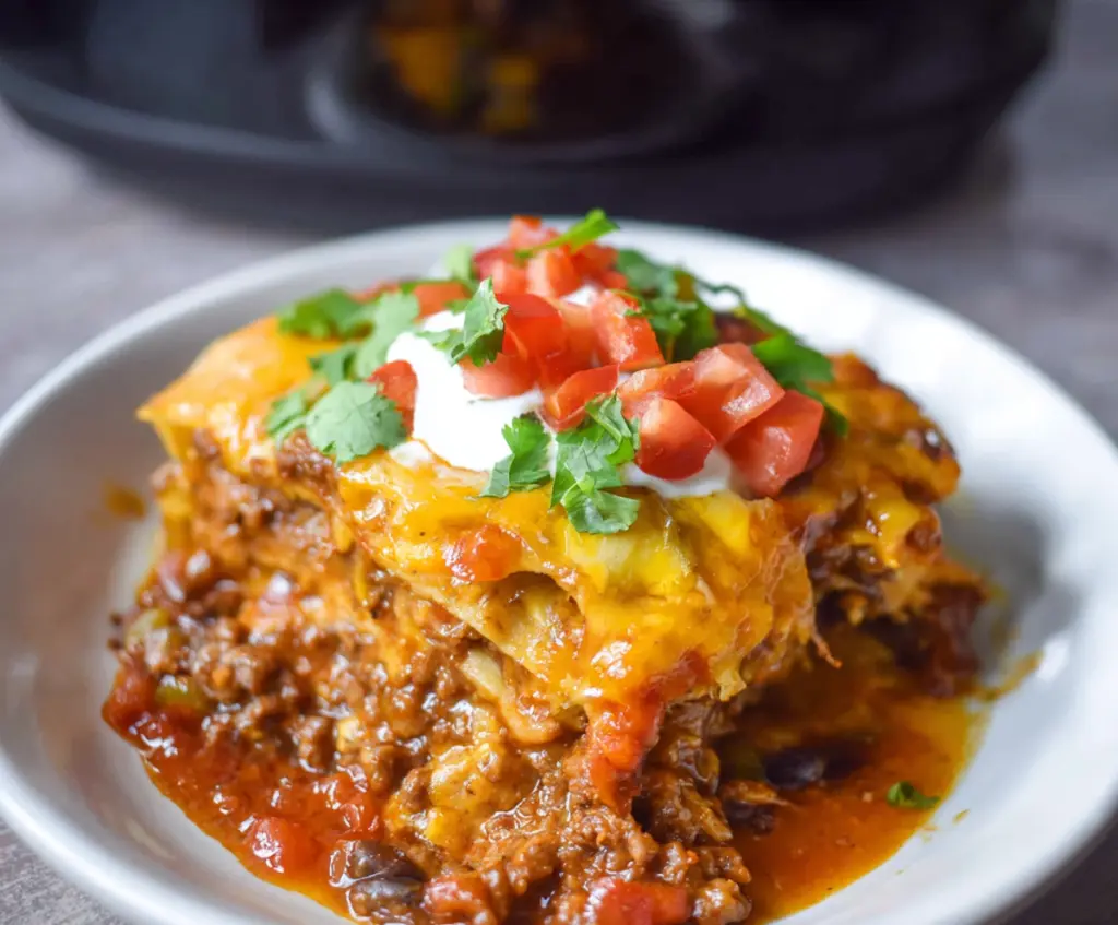 Delicious Crockpot Beef Enchilada Casserole topped with melted cheese and fresh cilantro.