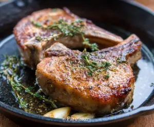 Juicy pan roasted pork chops with a golden crust served on a plate.